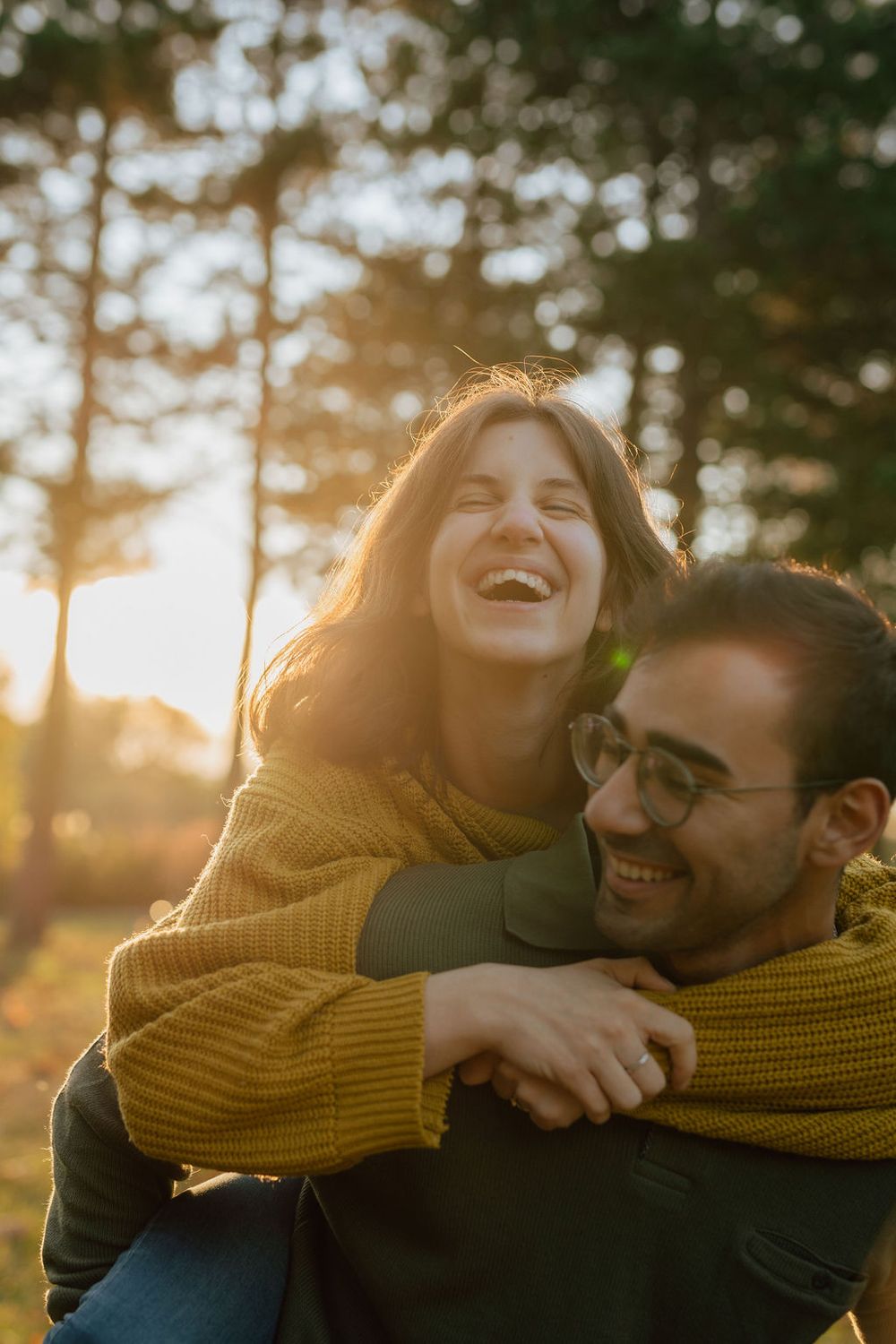 Joyful piggyback ride captured during golden hour in a forest setting.