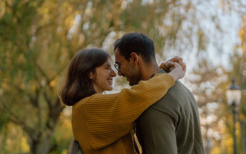 Couple in yellow and grey sweaters sharing an intimate moment in autumn.