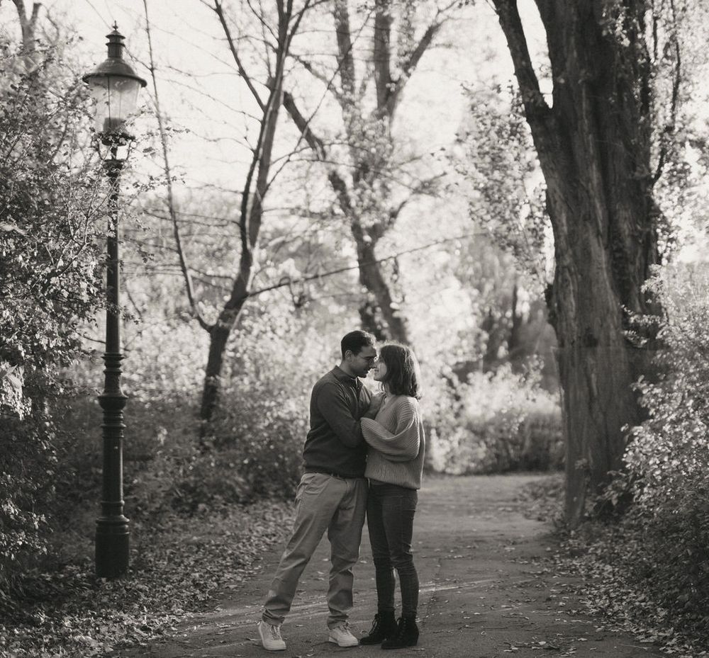 Couple in a tender embrace on a misty path with vintage streetlamp.