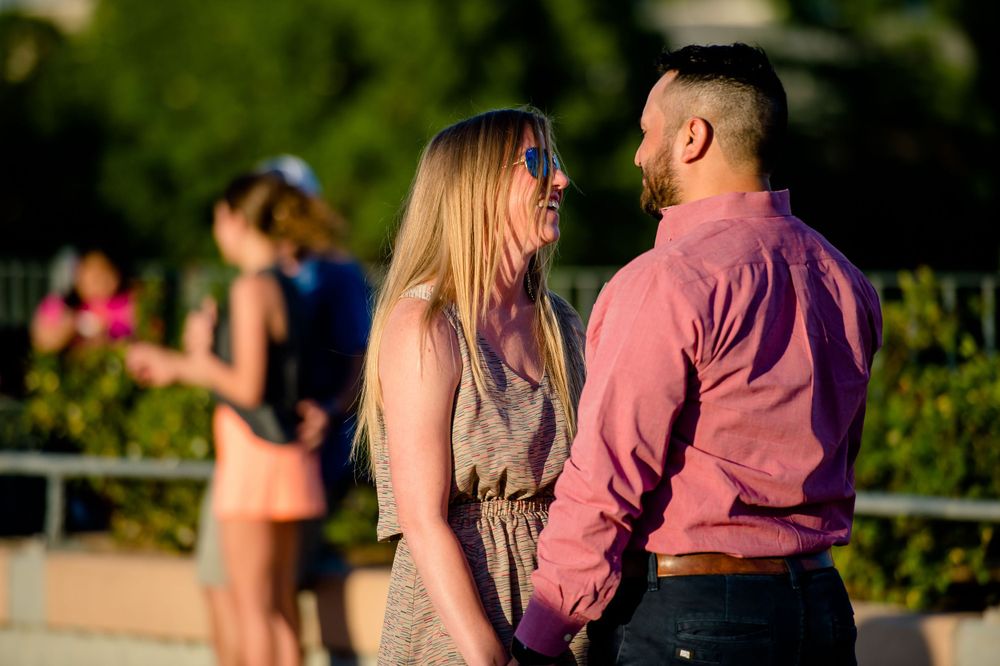 A couple shares an intimate moment in a garden with pink flowers blooming nearby.
