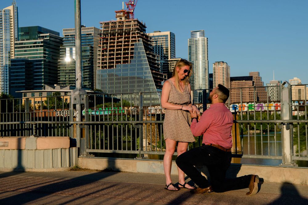 A proposal moment captured on a bridge with downtown Austin's skyline in the background.