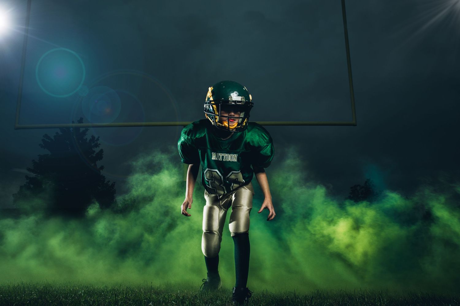 Mattoon football player in front of green smoke and goal posts in the background, stands ready to tackle for his team. Full drama portraits.