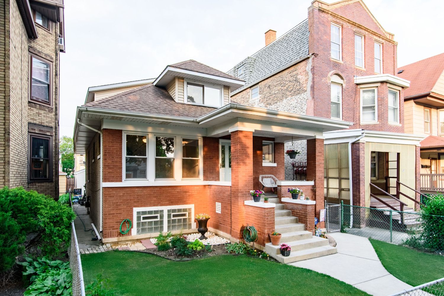 Brick Chicago bungalow style home with front porch and manicured lawn.