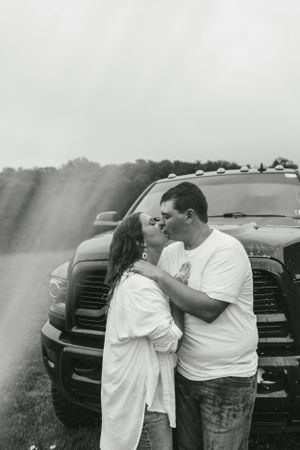 A tender moment between a couple standing in front of a pickup truck.