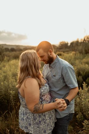 Intimate couple embracing in a field during golden hour sunset.