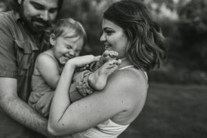 Black and white intimate portrait of family sharing tender moment outdoors.