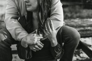 Black and white intimate photo of couple sitting close together outdoors.