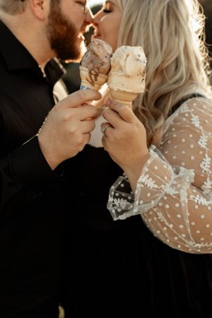 Close-up shot of a couple enjoying ice cream cones together in warm lighting.