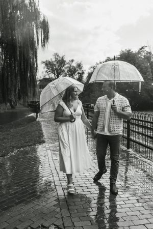 A couple walks together with clear umbrellas on a rainy day.