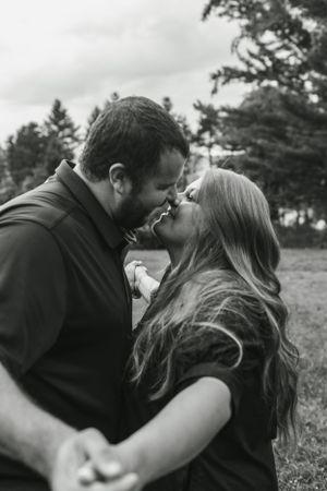 Romantic black and white portrait of a couple sharing an intimate moment in a natural outdoor setting.