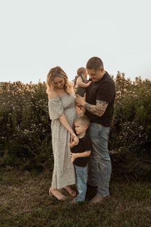 A family stands close together in a field during golden hour.