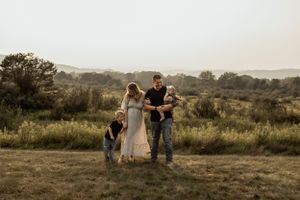 A family poses together on a hilltop with rolling countryside views in the background.