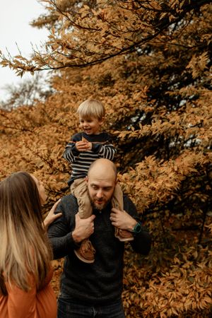 Playful family moment captured against vibrant orange fall foliage.