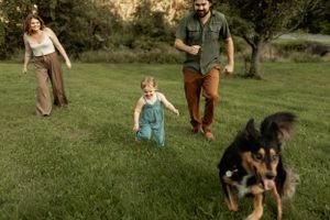 Family walking together with their dog on grassy field during sunset.