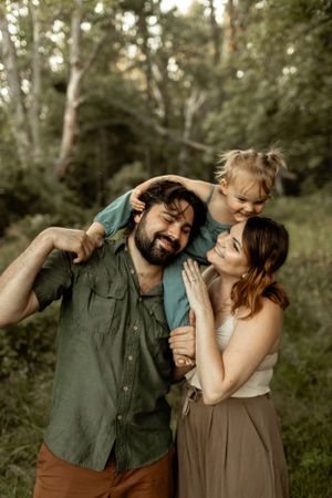 Family shares a joyful candid moment together in a wooded outdoor setting during golden hour.