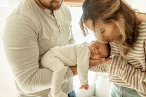 A gentle family moment with a small baby being held in a cozy indoor setting.