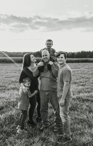 A family poses together for a portrait in an open field at sunset.