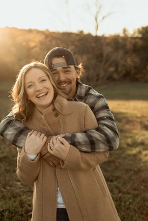 A joyful couple embracing outdoors during golden hour with warm sunlight illuminating their laughter.