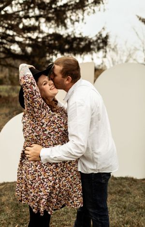 Intimate outdoor portrait of couple embracing against white curved wall.