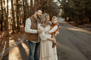 A tender family moment captured on a sunlit forest path during autumn.