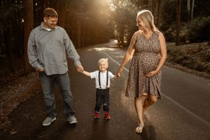 Family walking together on a tree-lined road during sunset.