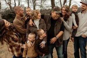 A candid outdoor family photo showing multiple generations sharing laughter in autumn setting.
