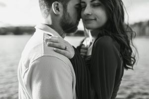 Romantic black and white photo of couple embracing at sunset.
