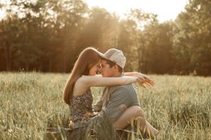 A romantic couple embraces in a sunlit meadow during golden hour.