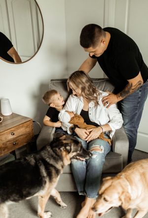 Family gathering in living room with two dogs looking up at their owners.