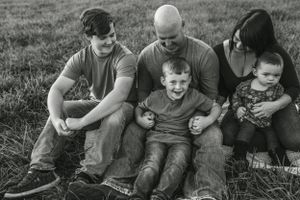 A family sits together on grass enjoying a casual outdoor moment.