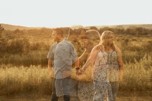 Couple holding hands during golden hour in a rustic field setting.