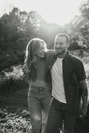 Intimate black and white photo of couple sharing a joyful moment outdoors in natural lighting.