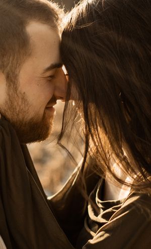 Intimate close-up portrait of couple with sun backlighting their faces.