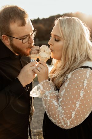 A couple shares ice cream cones together during a romantic sunset photoshoot.