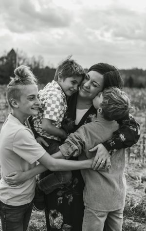 Black and white photo of joyful group hug in outdoor field setting.