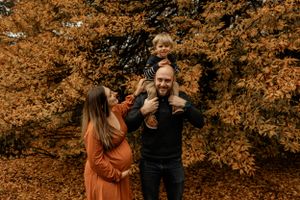 Family enjoying autumn weather with golden foliage in background.