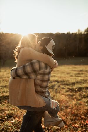 A playful embrace captured in silhouette against a golden sunset in an autumn field.