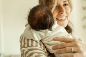 A tender moment between parent and baby wearing matching striped outfits in soft natural light.