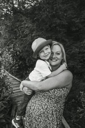 Black and white portrait showing joyful embrace between parent and child outdoors.