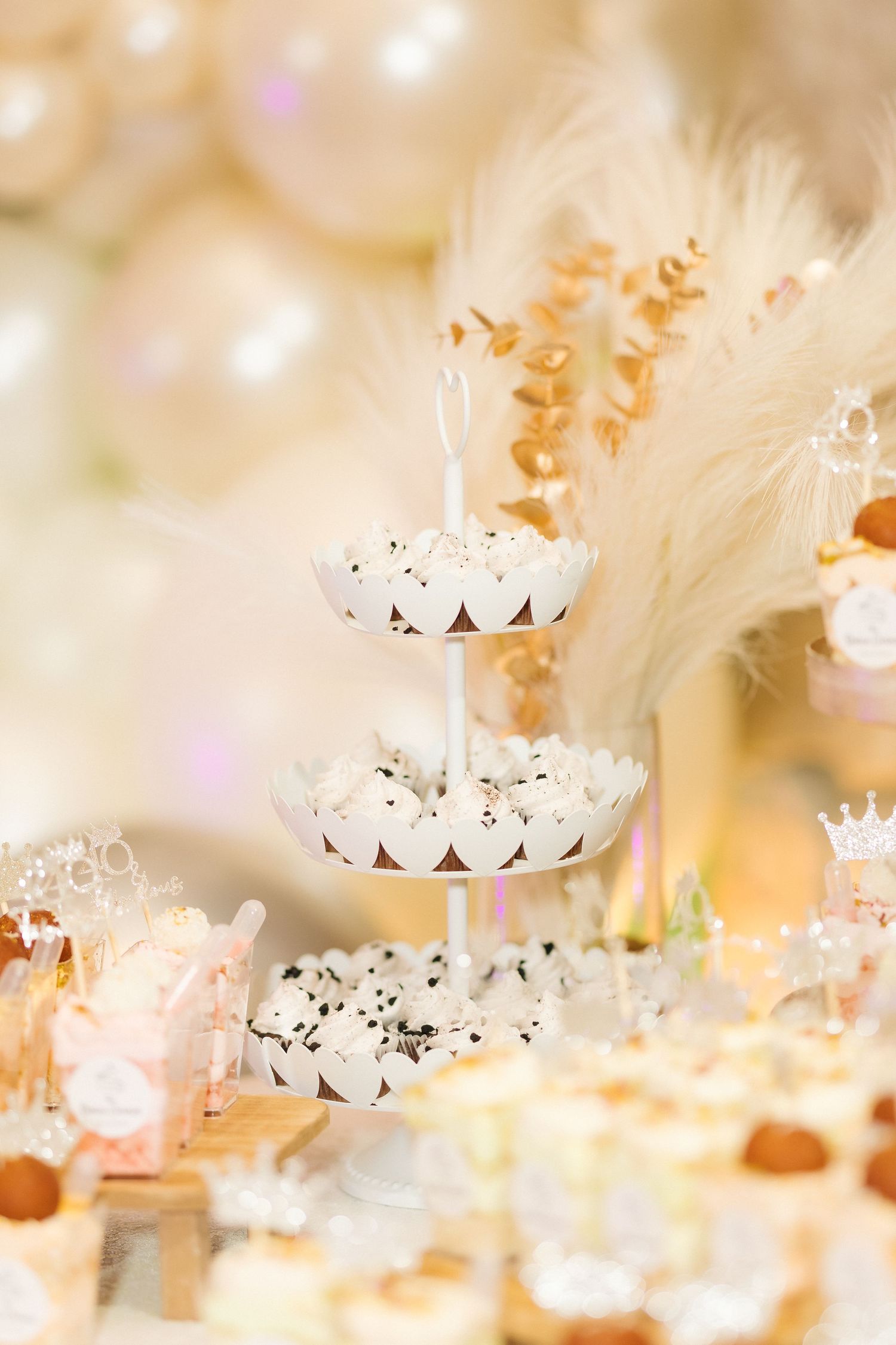 Elegant dessert display with tiered white treats and feather decorations.