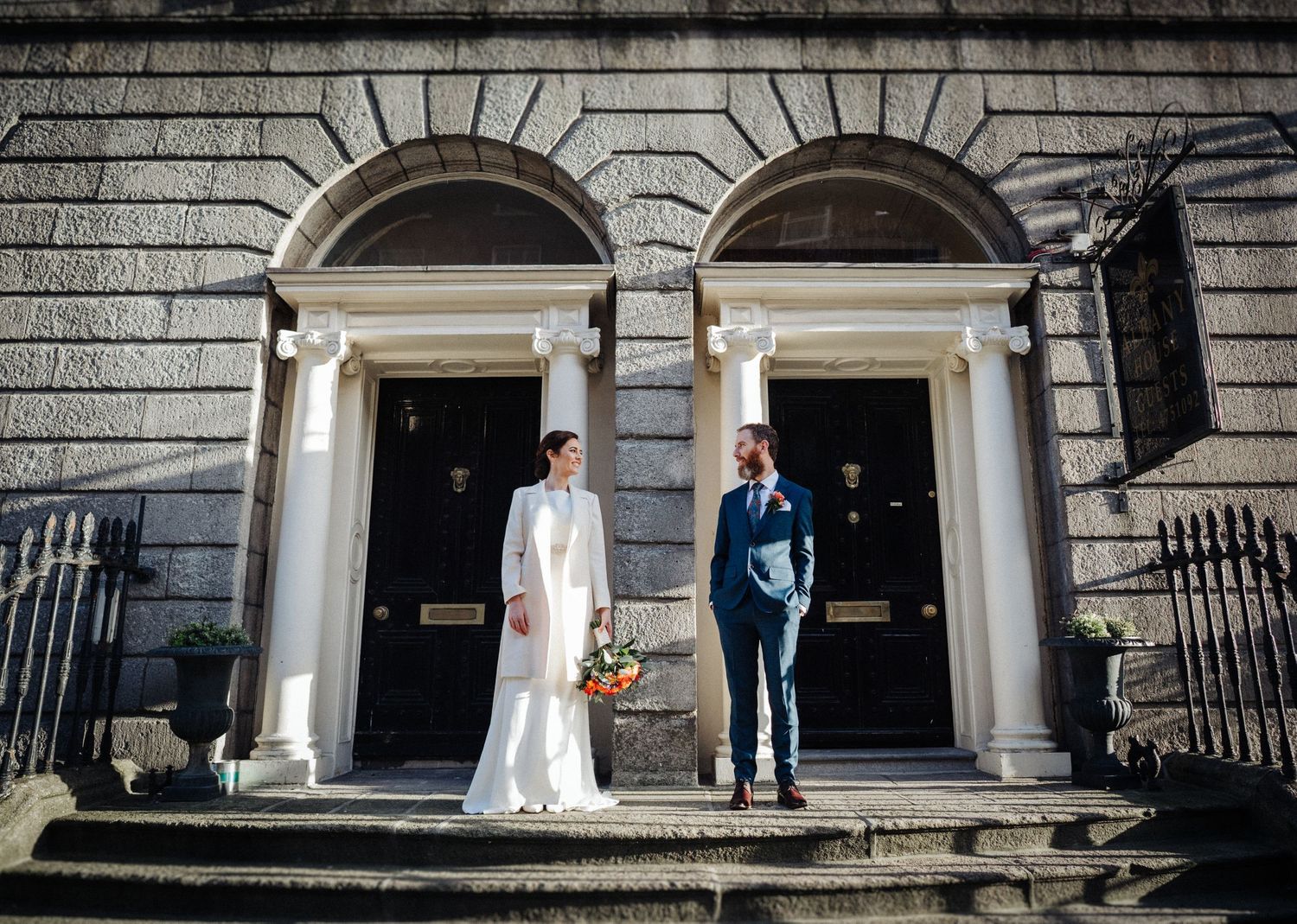 A couple stands in front of grand Georgian doorways with stone archways.