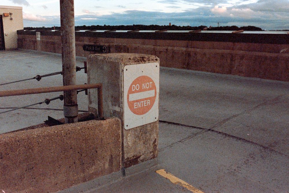 A faded orange parking sign on a concrete barrier at sunset.