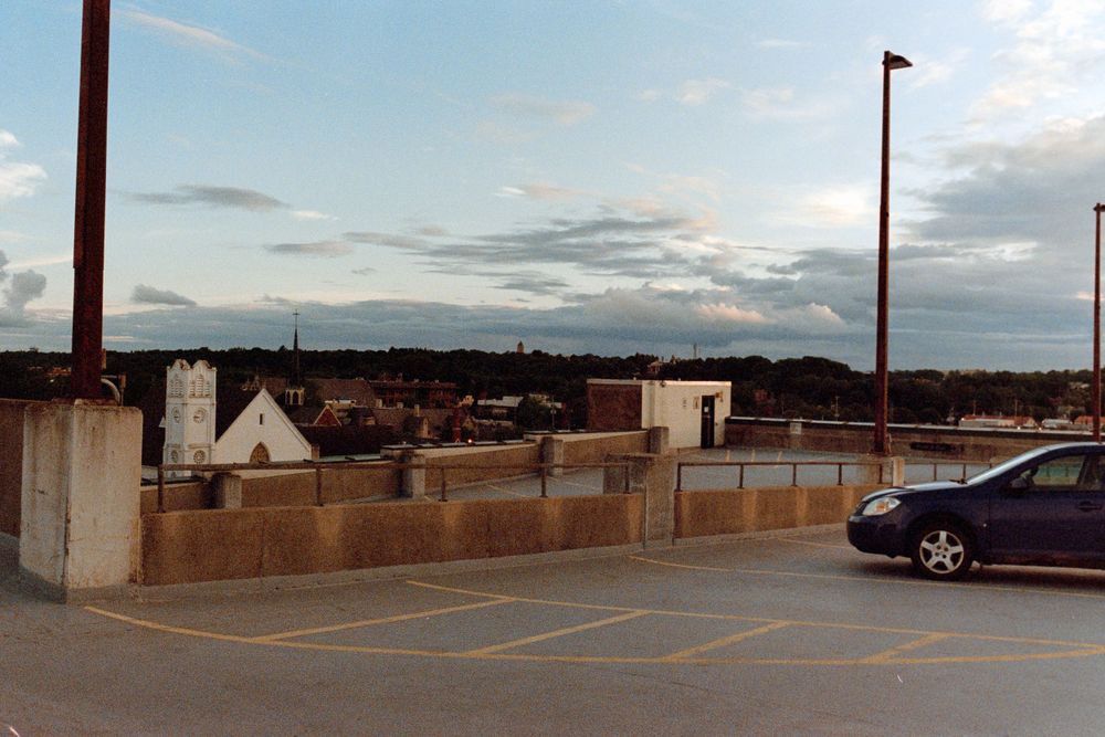 Rooftop parking area overlooking city buildings during sunset.