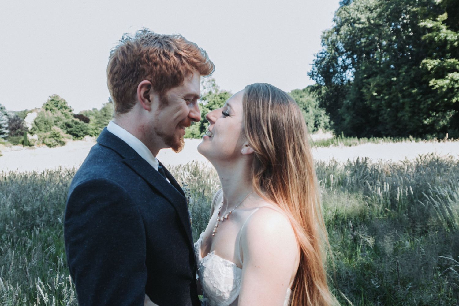 Bride and Groom smiling at one another in a field