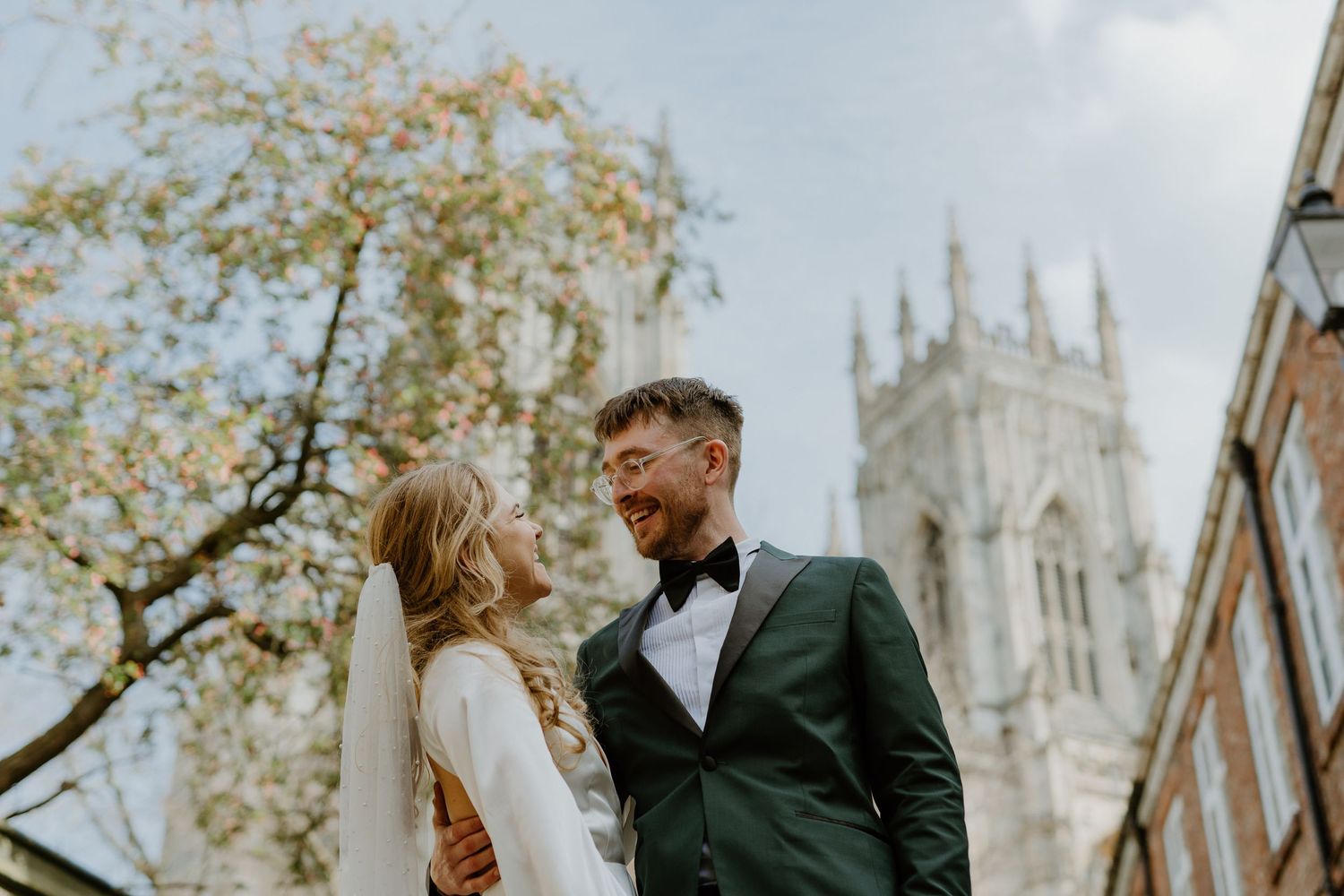 Wedding couple shares intimate moment with historic church tower in background.