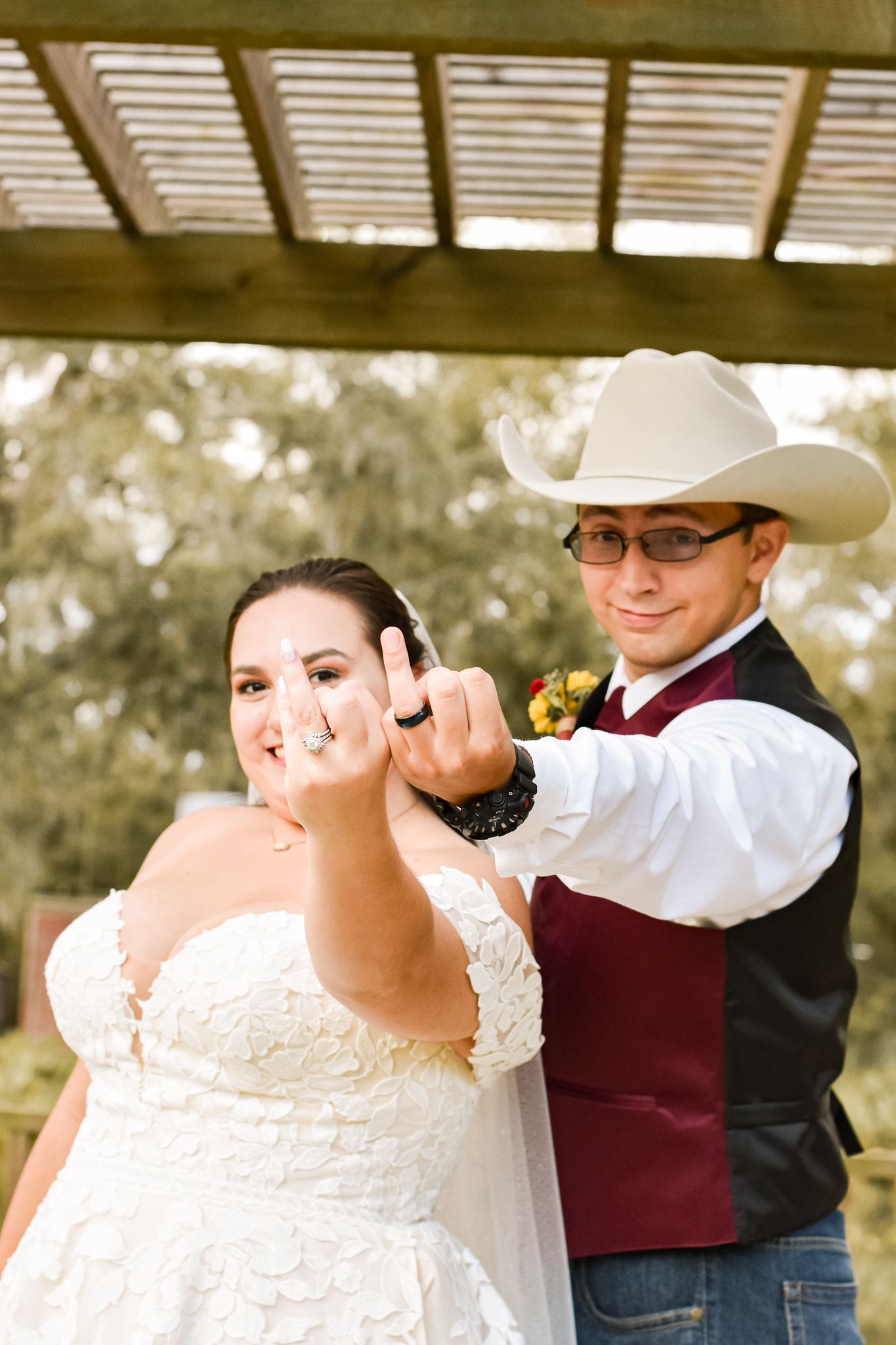 Wedding couple poses playfully during their rustic outdoor photoshoot.