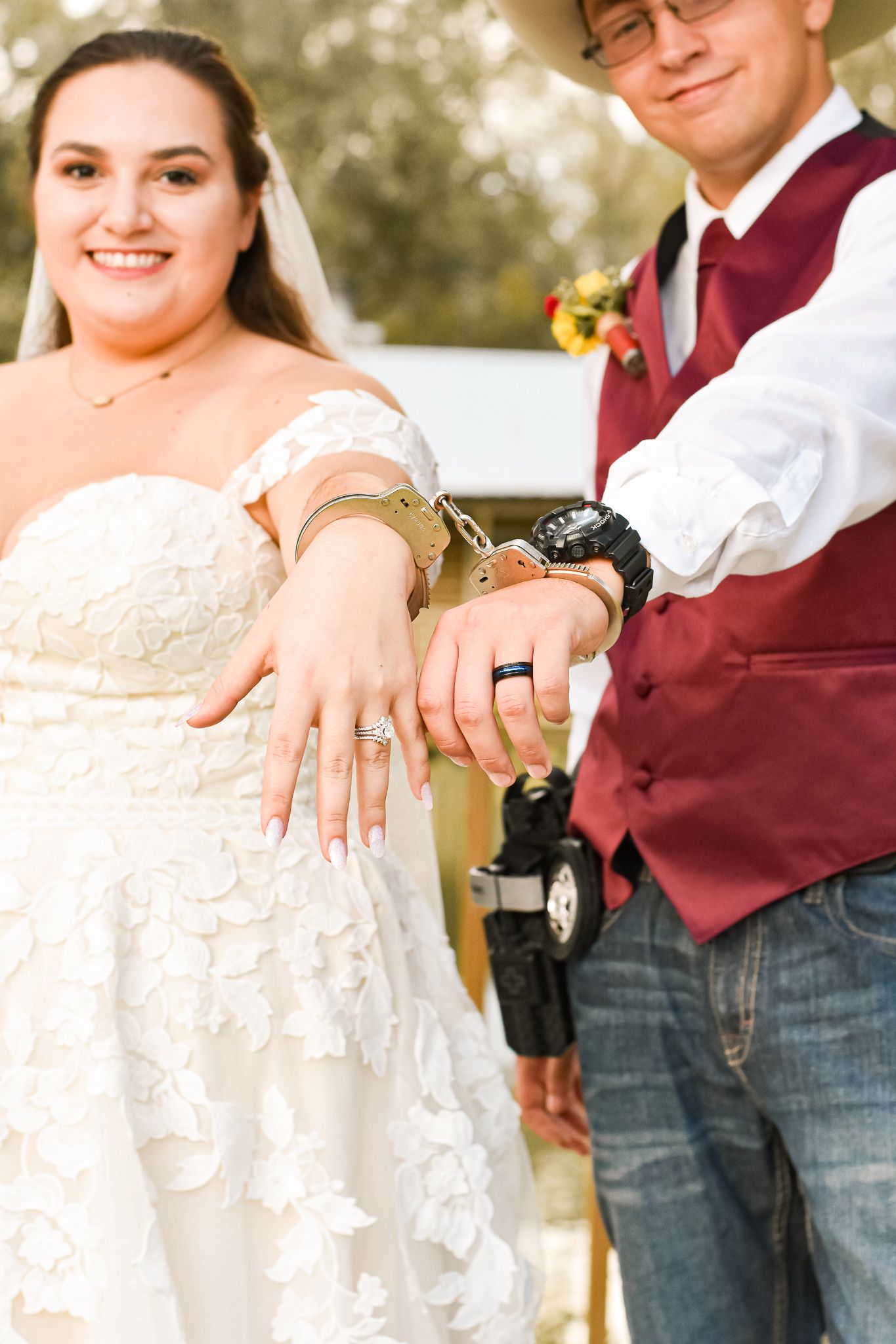 Newlyweds showing off their wedding rings in front of rustic backdrop.