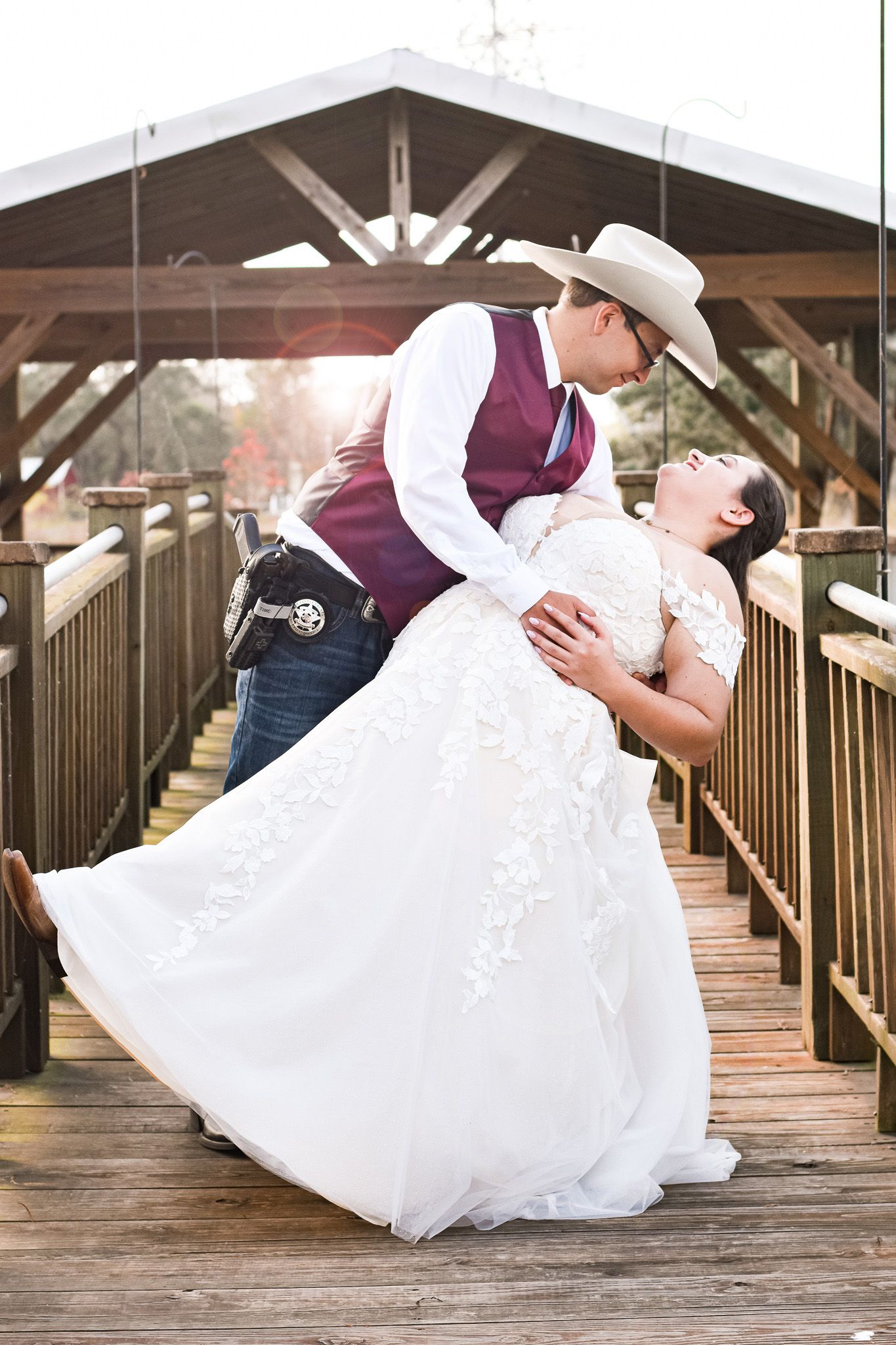 A romantic wedding portrait on a wooden bridge with western-themed attire.