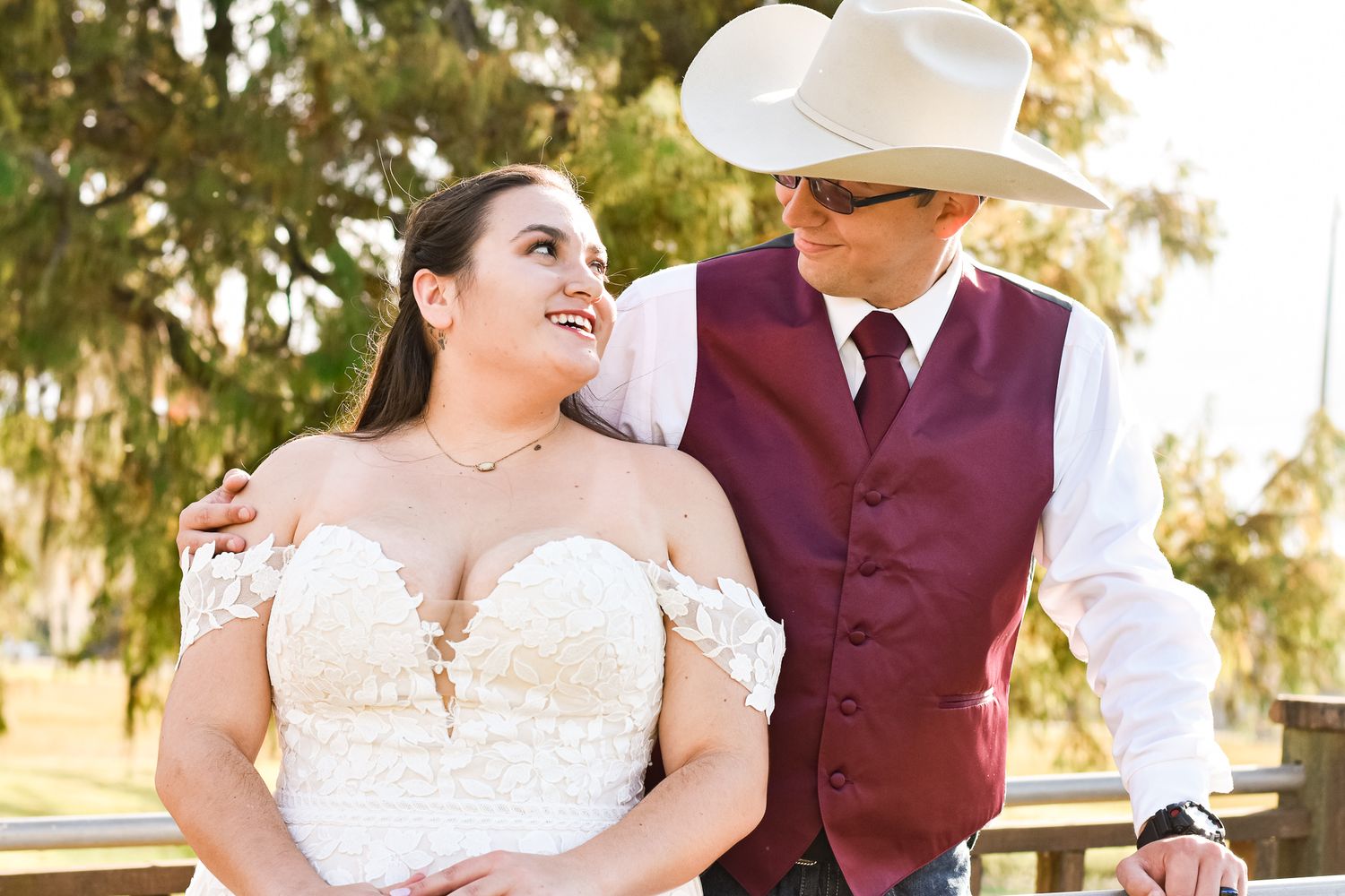 A couple shares a tender moment in western wedding attire against a natural backdrop.
