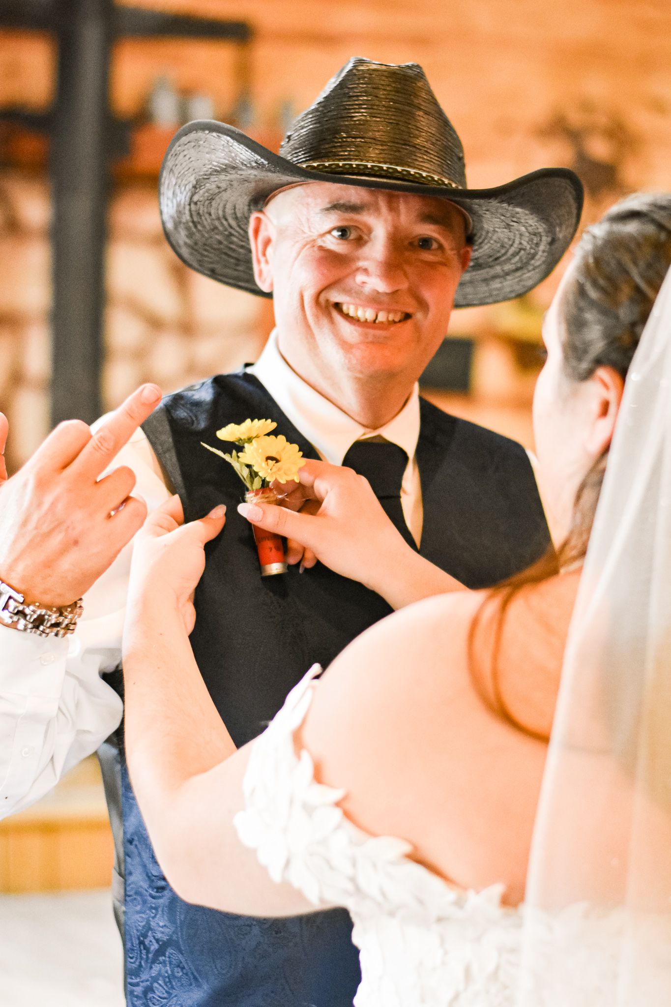 Candid moment of boutonniere pinning during western-themed wedding ceremony.